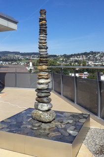 Säulenbrunnen mit Flusssteinen auf Terrasse